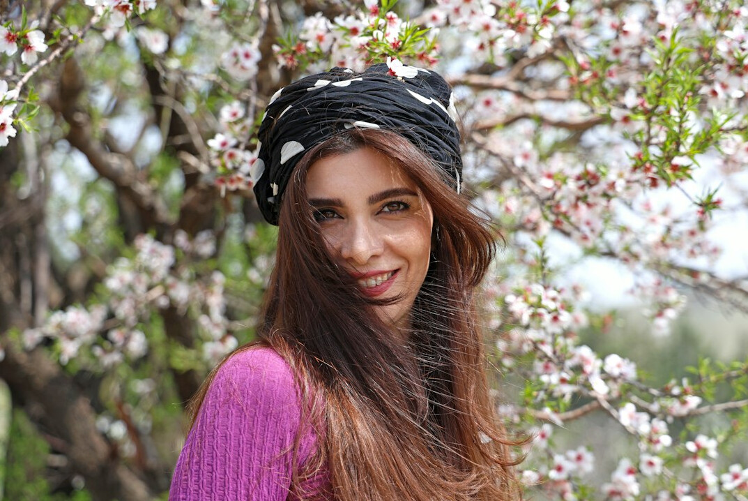 Smiling young woman with long brown hair in a scarf outdoors